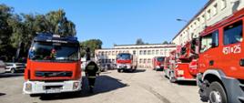 Pięć samochodów ratowniczo-gaśniczych na placu przed budynkiem szkoły