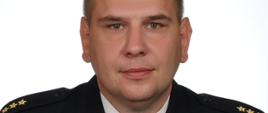 Na zdjęciu widać zdjęcie portretowe kpt. mgr Damiana Knopa. Mianowanego od 1 lipca 2021 roku Pełniącym Obowiązki Zastępcy Komendanta Miejskiego PSP w Kaliszu. Funkcjonariusz ubrany w umundurowanie wyjściowe.