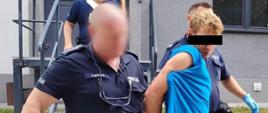 Zdjęcie przedstawia funkcjonariuszy policji prowadzących zatrzymanego podejrzanego