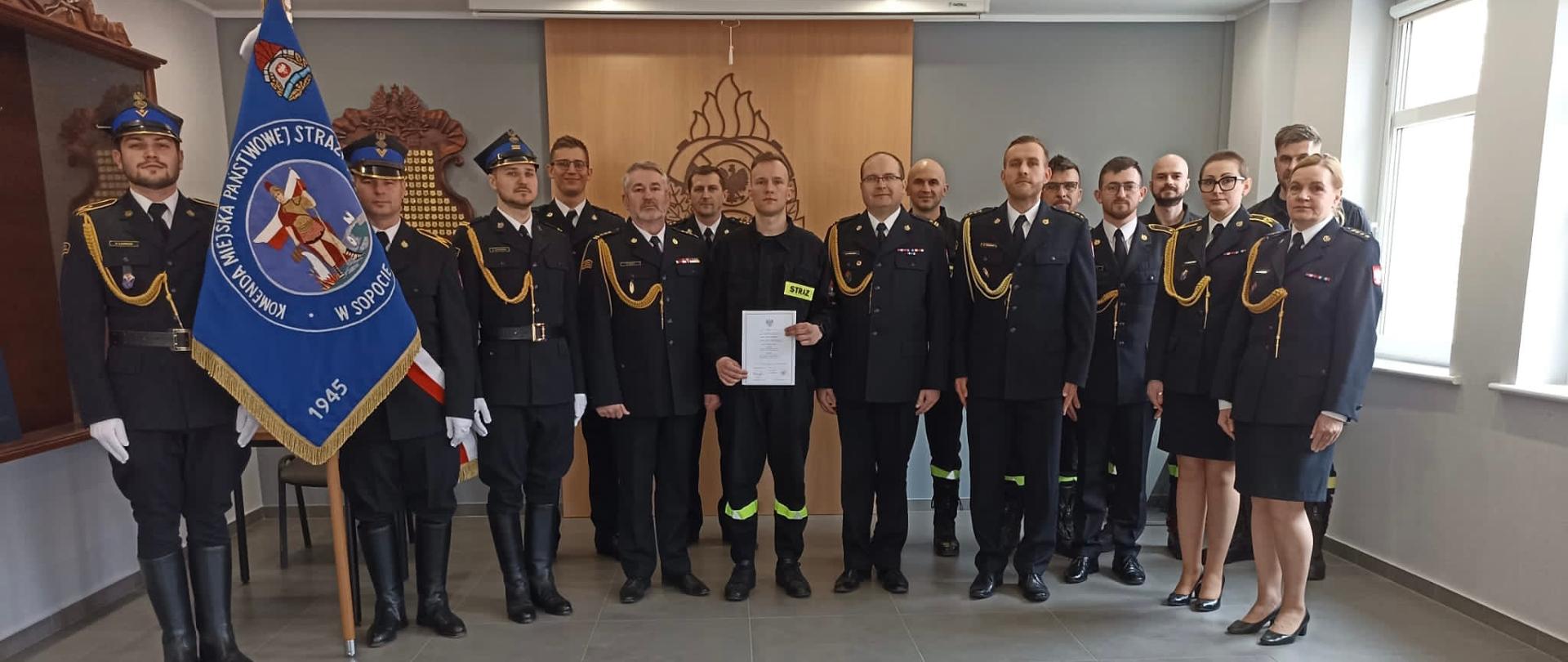 Strażak który złożył ślubowanie w towarzystwie komendantów i innych funkcjonariuszy oraz sztandaru