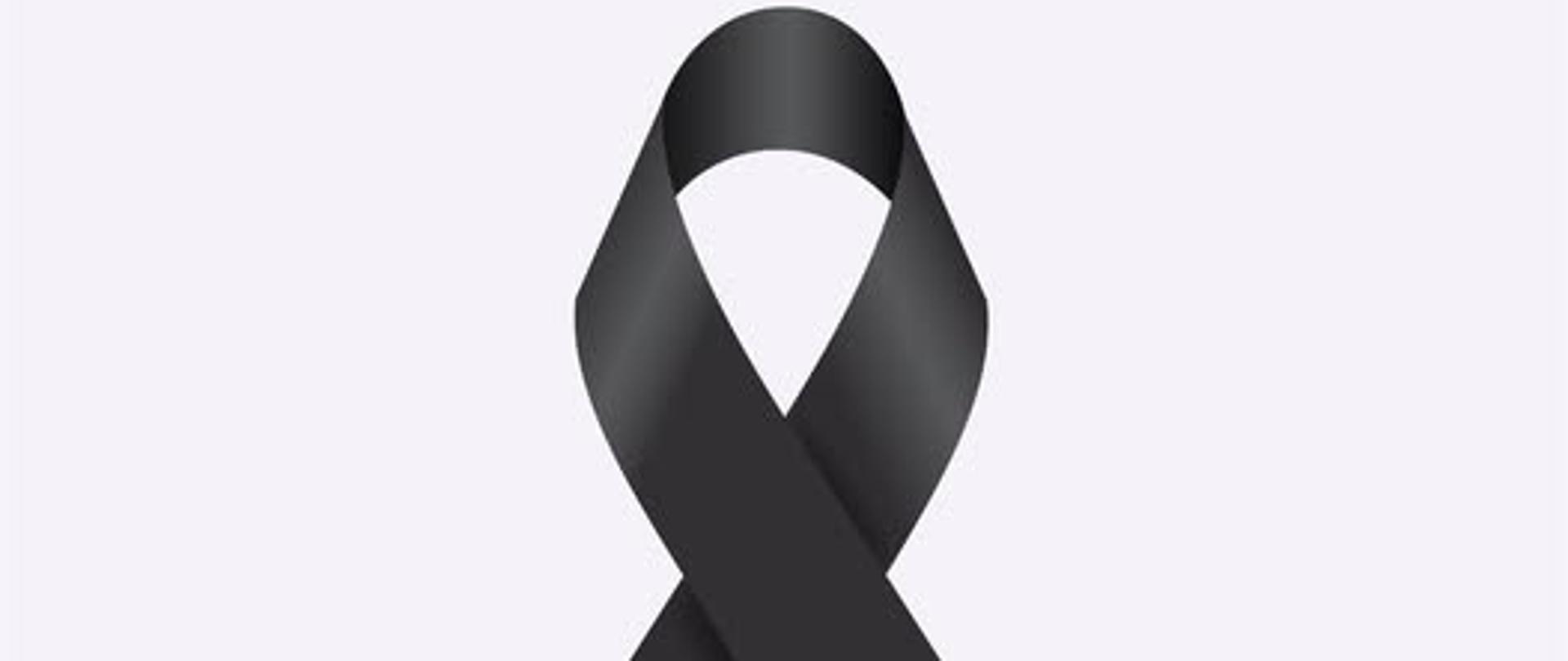 Na zdjęciu na białym tle po środku jest widoczna żałobną czarną wstążkę, która symbolizuje żałobę w kulturze euroamerykańskiej.