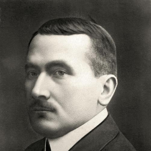 Roman Dmowski - czarno-biały półprofilowy portret mężczyzny, ciemna marynarka, ciemny krawat.