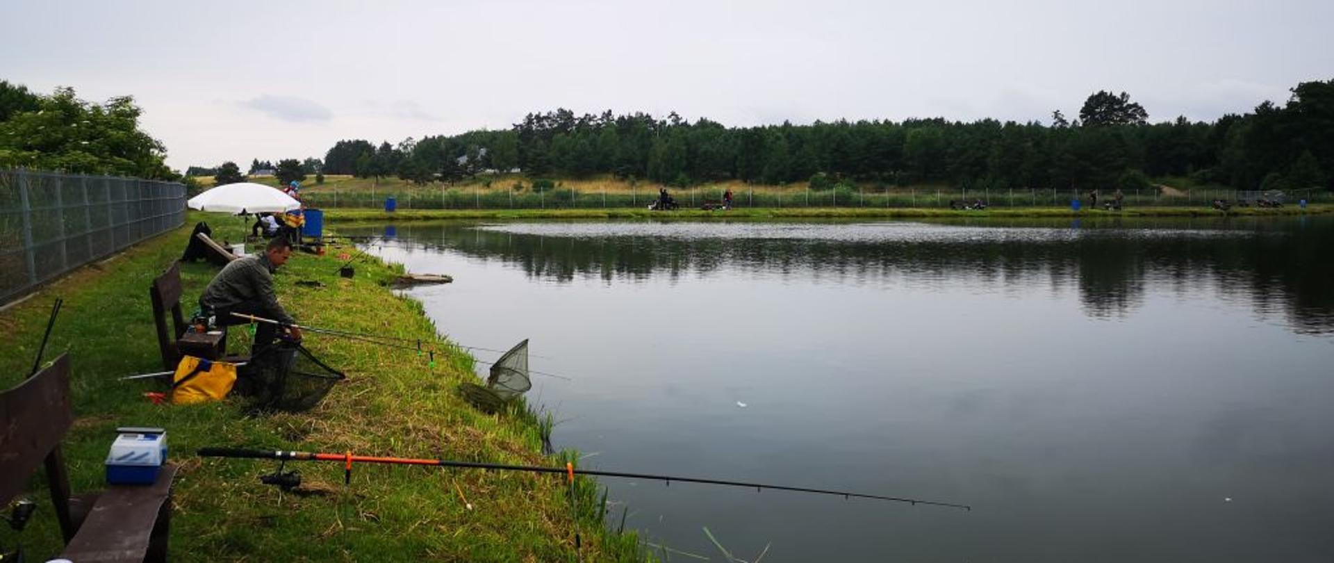 Słonecznie. Na zdjęciu widoczni strażacy podczas zawodów wędkarskich. 