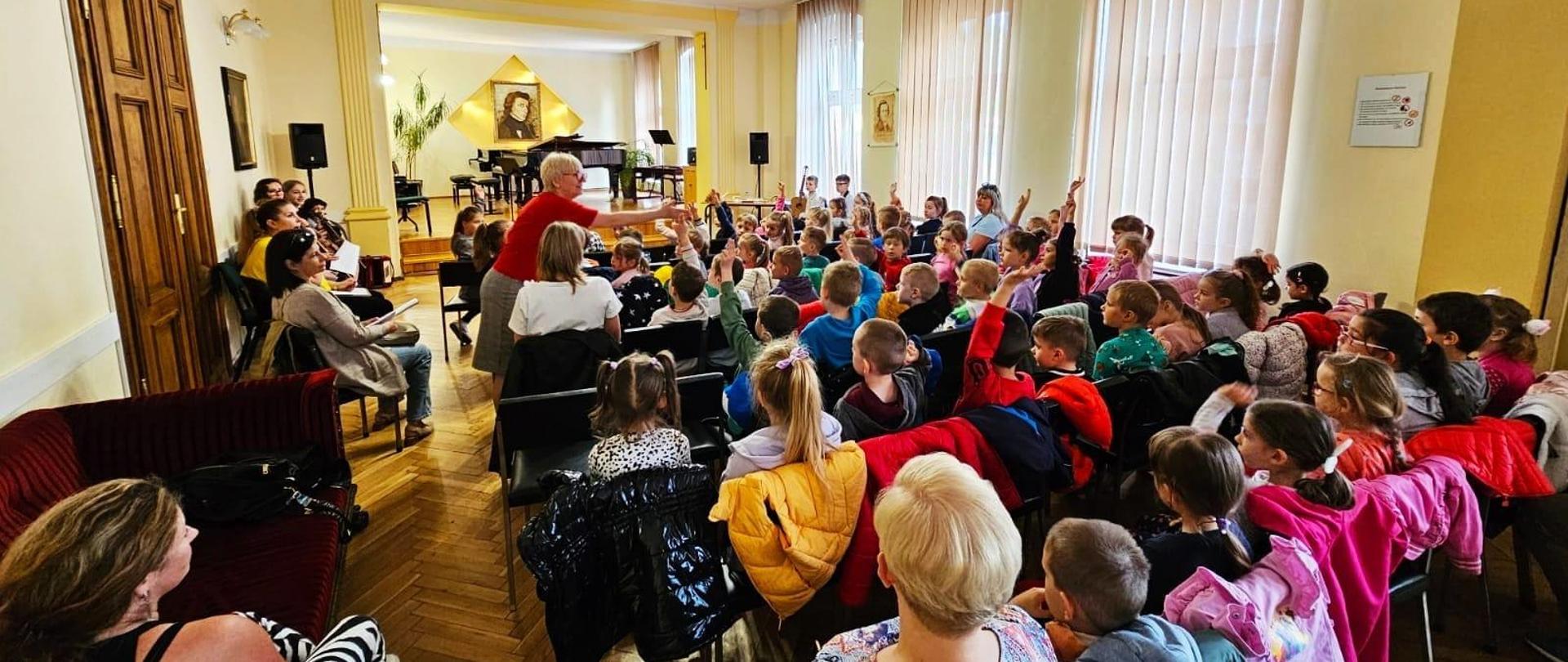 Galeria 14 zdjęć z audycji muzycznych, które odbyły się 10 maja w auli PSM w Kłodzku. Na zdjęciach uczniowie, którzy przyglądają się jak wygląda nauka w szkole muzycznej.