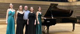Cztery młode kobiety w długich eleganckich sukniach i mężczyzna stoją przy fortepianie Fazioli na scenie sali koncertowej PSM w Jastrzębiu-Zdroju