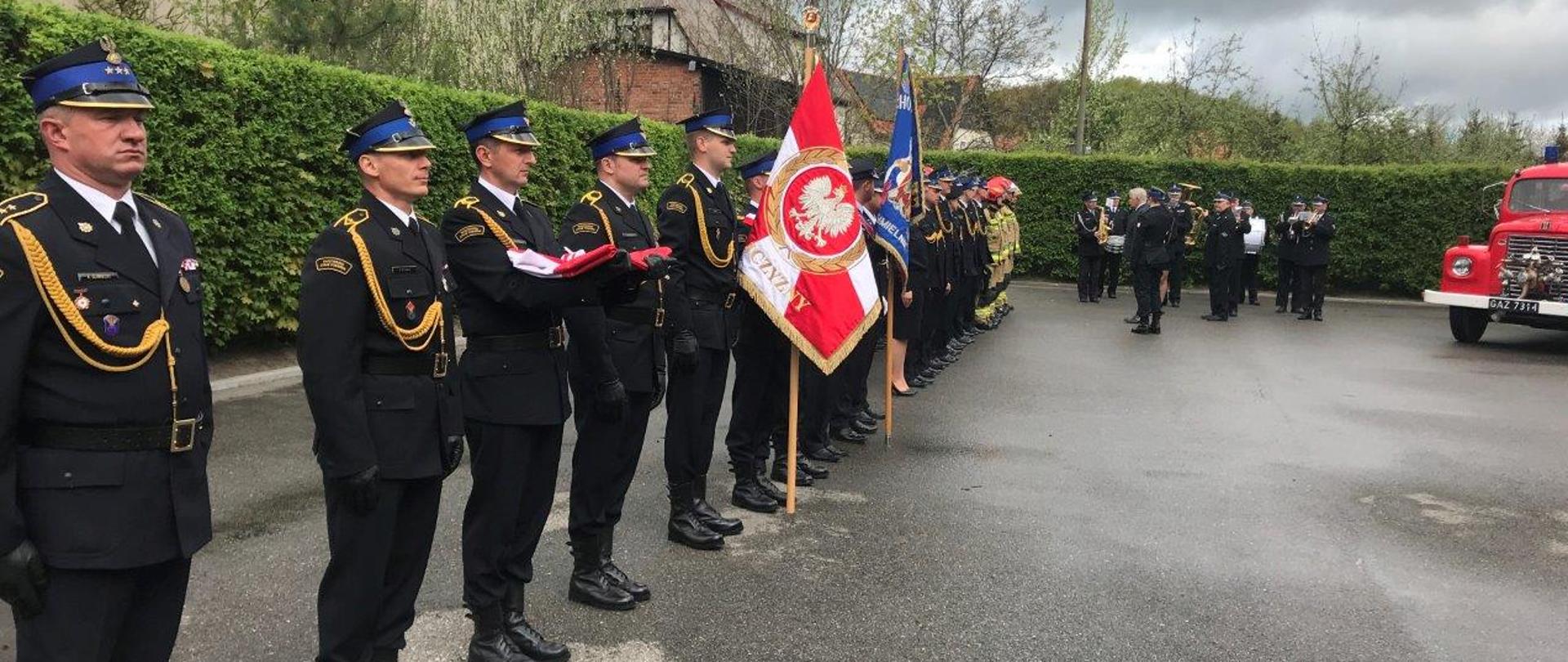 Dowódca pododdziału, za którym dalej w szeregu ustawiony jest poczet flagowy, poczty sztandarowe i strażacy