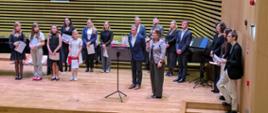 Jury i Dyrekcja szkoły wręczają na estradzie sali koncertowej nagrody Laureatom.