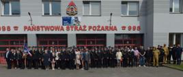 Uczestnicy uroczystości pozują do pamiątkowej fotografii przed budynkiem remizy
