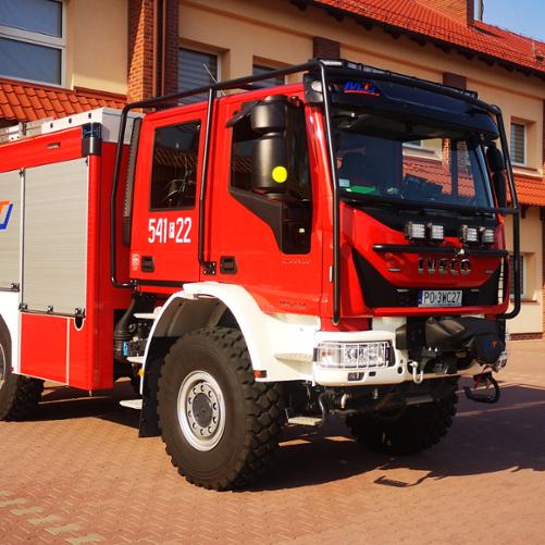 Na zdjęciu średni samochód gaśniczy marki IVECO przed budynkiem Jednostki Ratowniczo-Gaśniczej