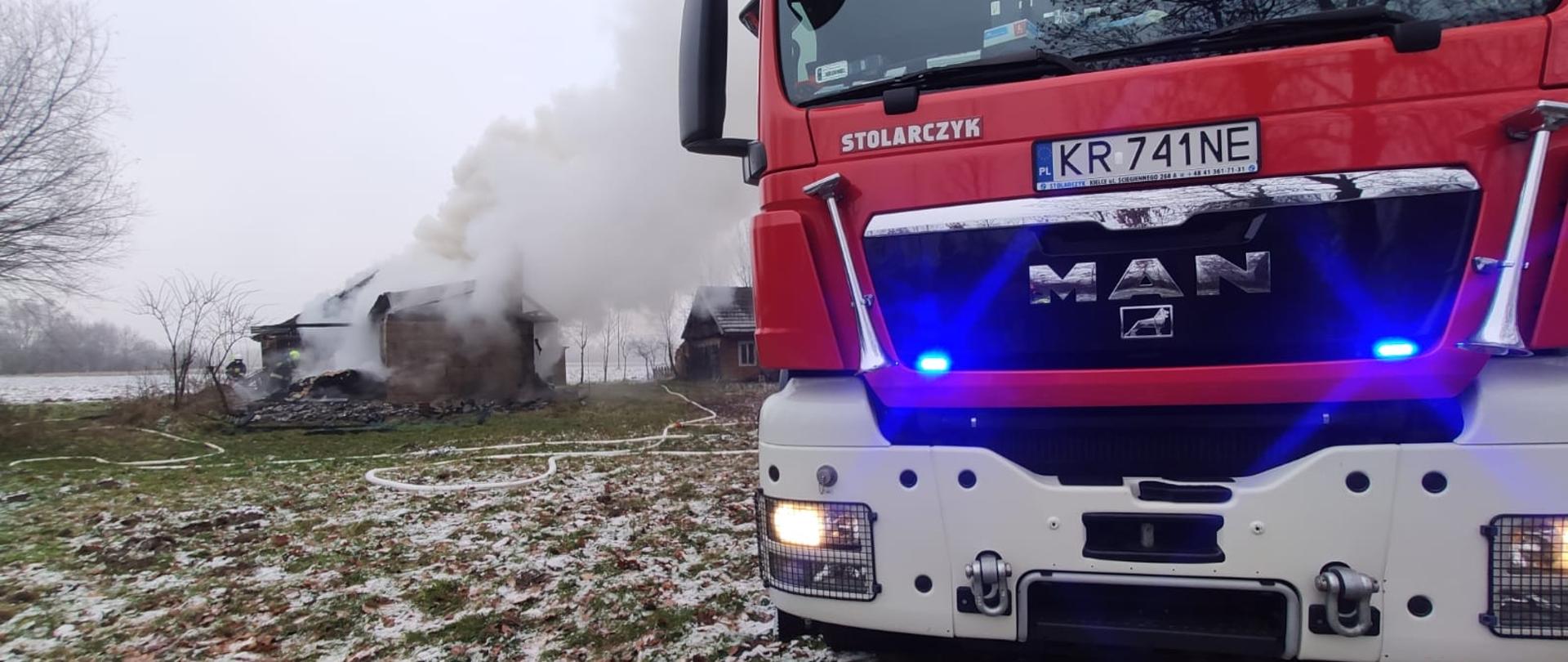 Na zdjęciu widoczny wóz strażacki, a w tle spalony budynek.