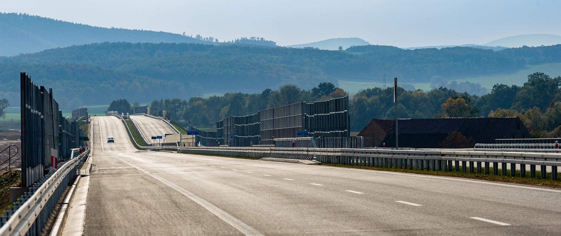 Na zdjęciu widoczne dwie jezdnie po dwa pasy ruchu plus pas awaryjny w każdym kierunku. Ekrany akustyczne częściowo w wzdłuż pasu rozdziału oraz po bokach jezdni