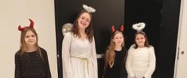 Cztery uczennice przebrane za aniołki i diabełki przed drzwiami sali koncertowej PSM