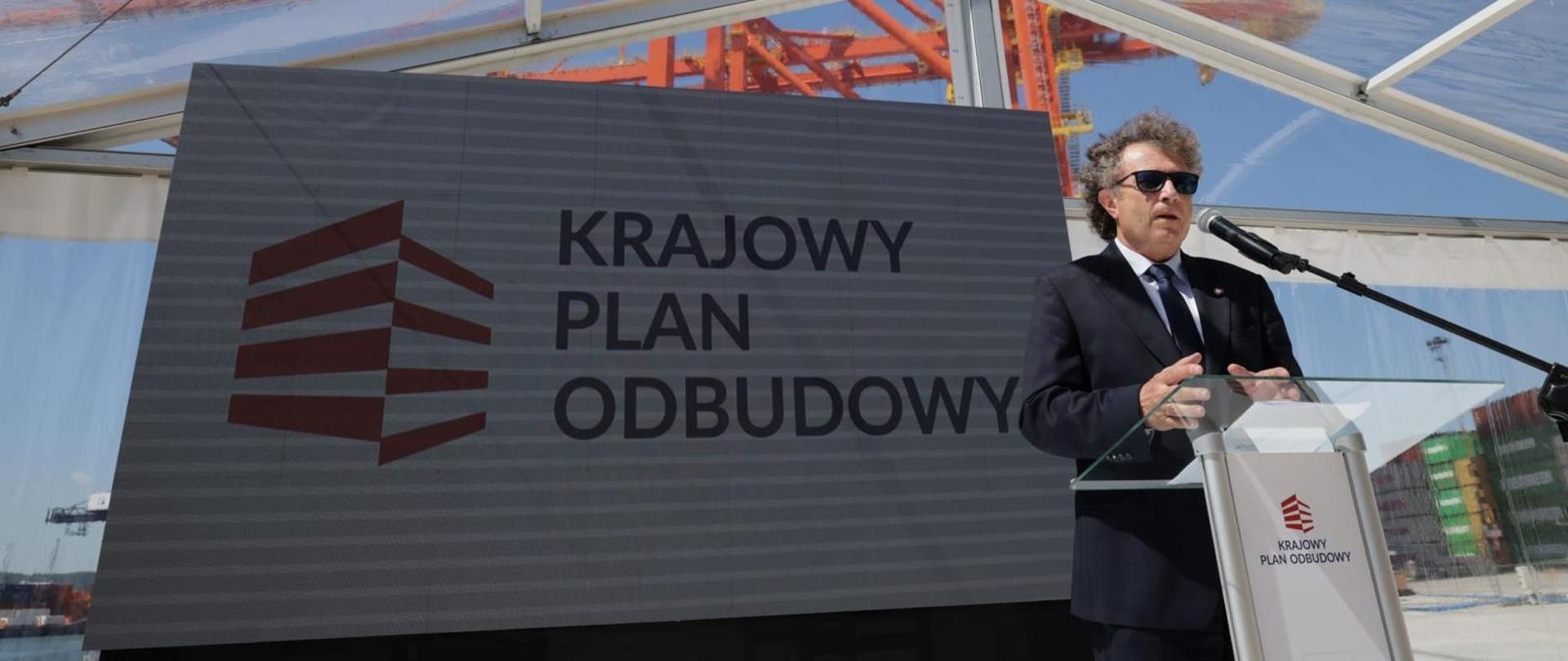 Na zdjęciu wiceminister Jacek Karnowski w Porcie Gdynia, przed mikrofonem odpowiada na pytania dziennikarzy