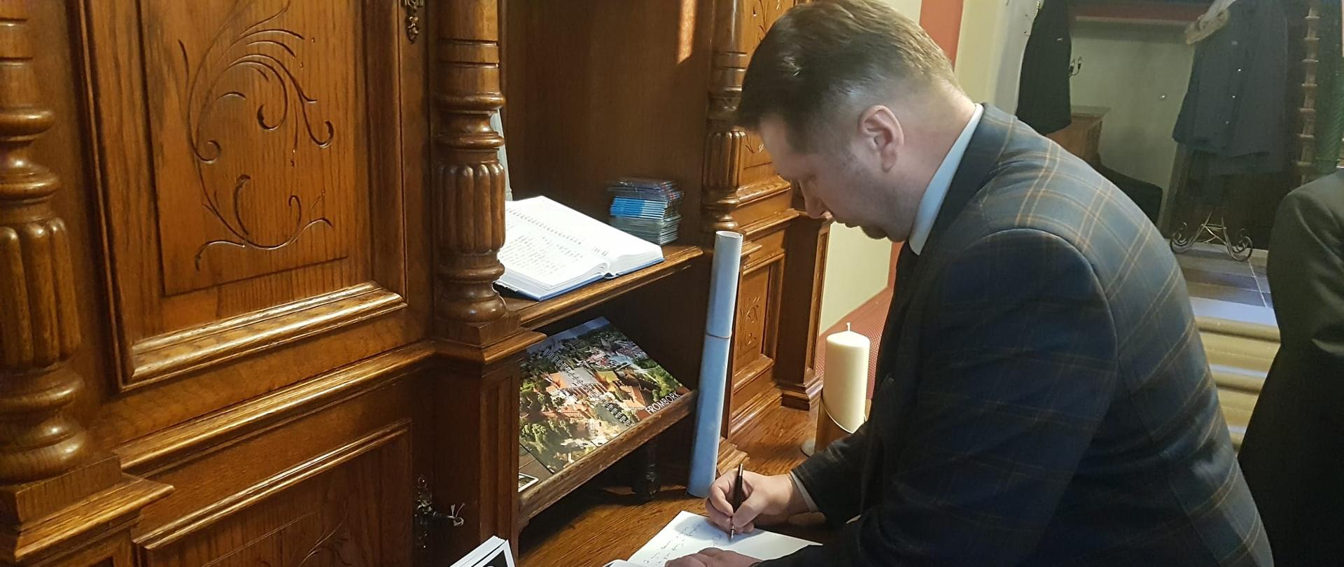 Minister Przemysław Czarnek z wizytą we Fromborku, minister Przemysław Czarnek wpisuje się do księgi pamiątkowej w Nowym Pałacu Biskupim. 