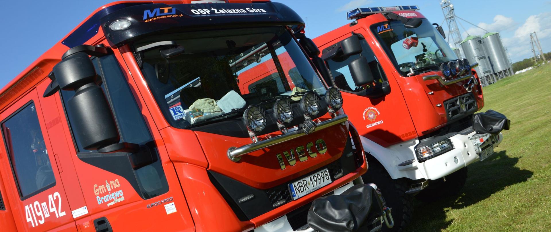 Zdjęcie zrobione po skosie, na nim dwa przody czerwonych aut pożarniczych.