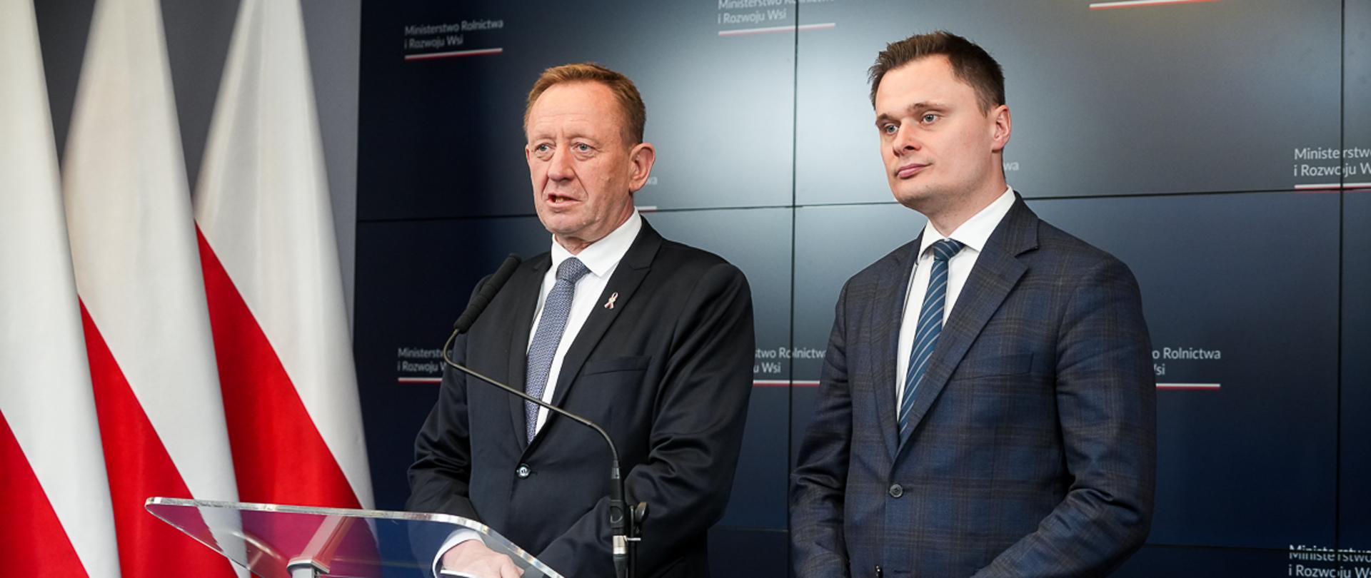 Minister Robert Telus oraz podsekretarz stanu Krzysztof Ciecióra, stojący przy mównicy