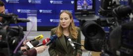 In the photo, Minister Katarzyna Pełczyńska-Nałęcz answers journalists' questions in front of their microphones