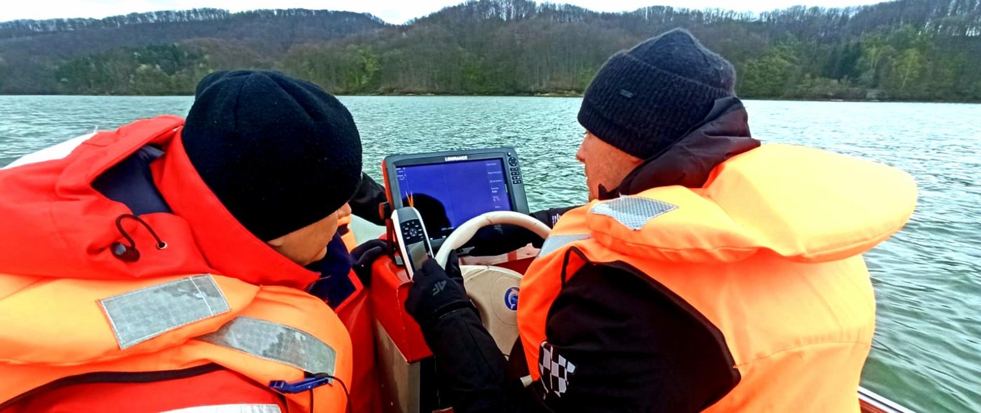 Zdjęcie zrobione na zewnątrz, podczas ćwiczeń strażaków na akwenie. Strażacy ćwiczą z użyciem specjalistycznego sonaru.
