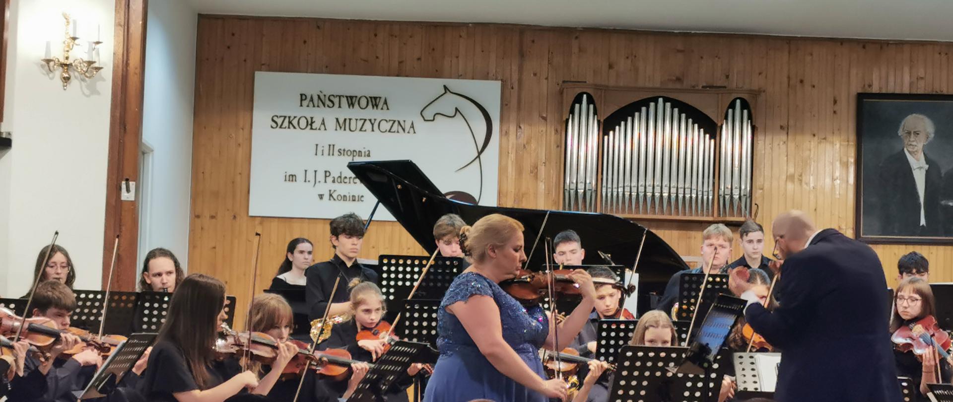 na scenie orkiestra oraz skrzypaczka podczas koncertu