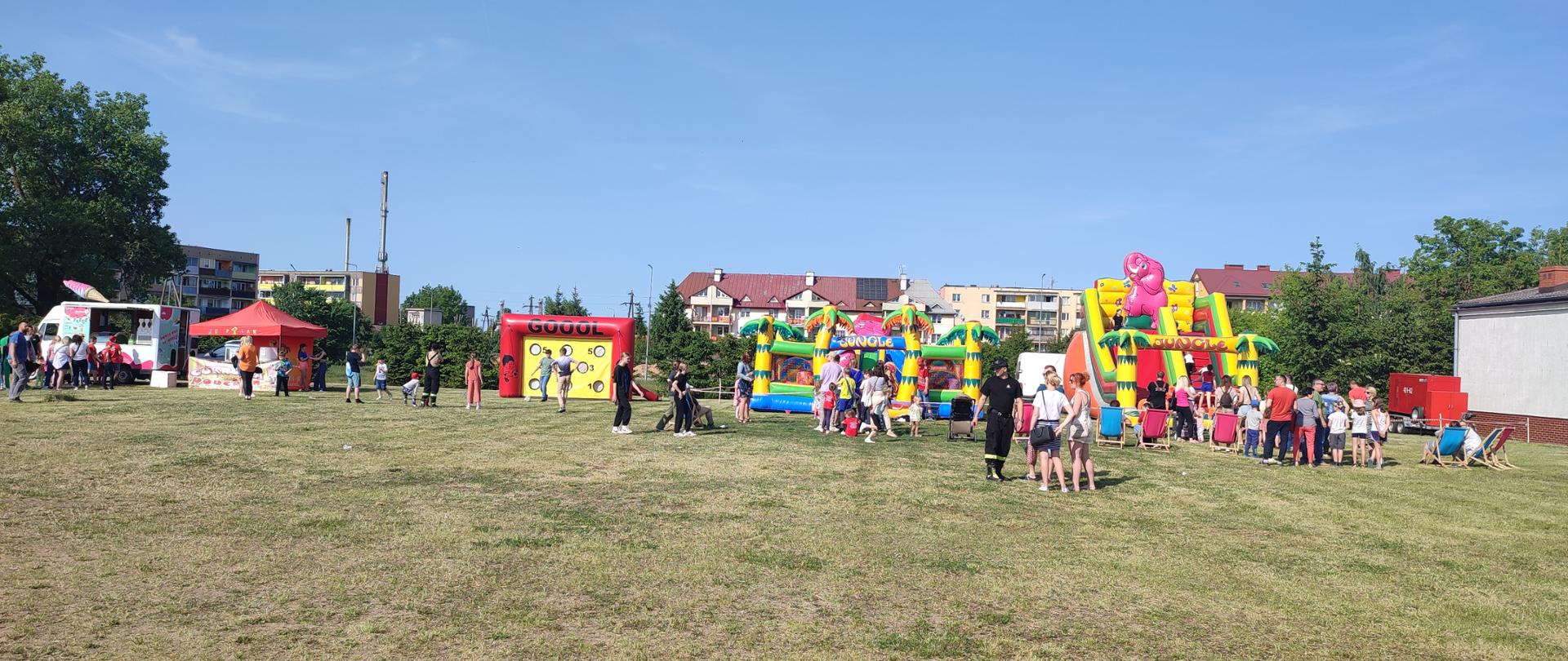 Pompowane atrakcje dla dzieci oraz uczestnicy pikniku.
