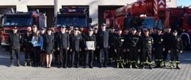Wspólne zdjęcie pamiątkowe wszystkich uczestniczących w uroczystości. W tle samochody pożarnicze.