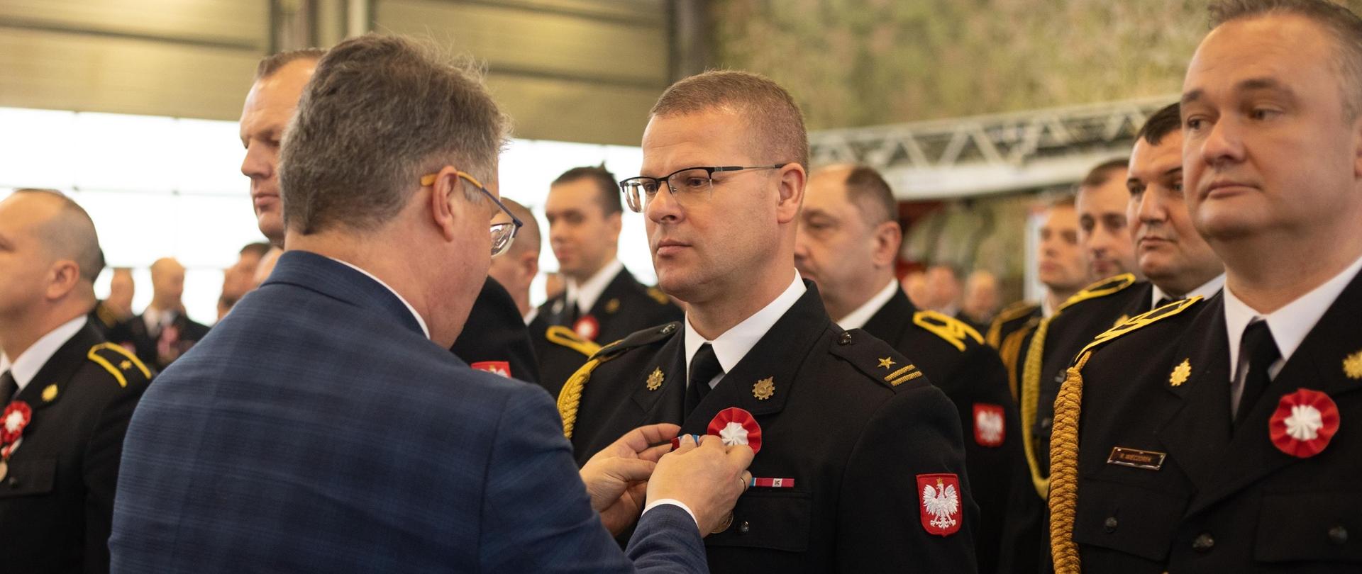 Sekretarza Stanu w MSWiA Pana Maciej Wąsik przypina odznakę wyróżnionemu funkcjonariuszowi