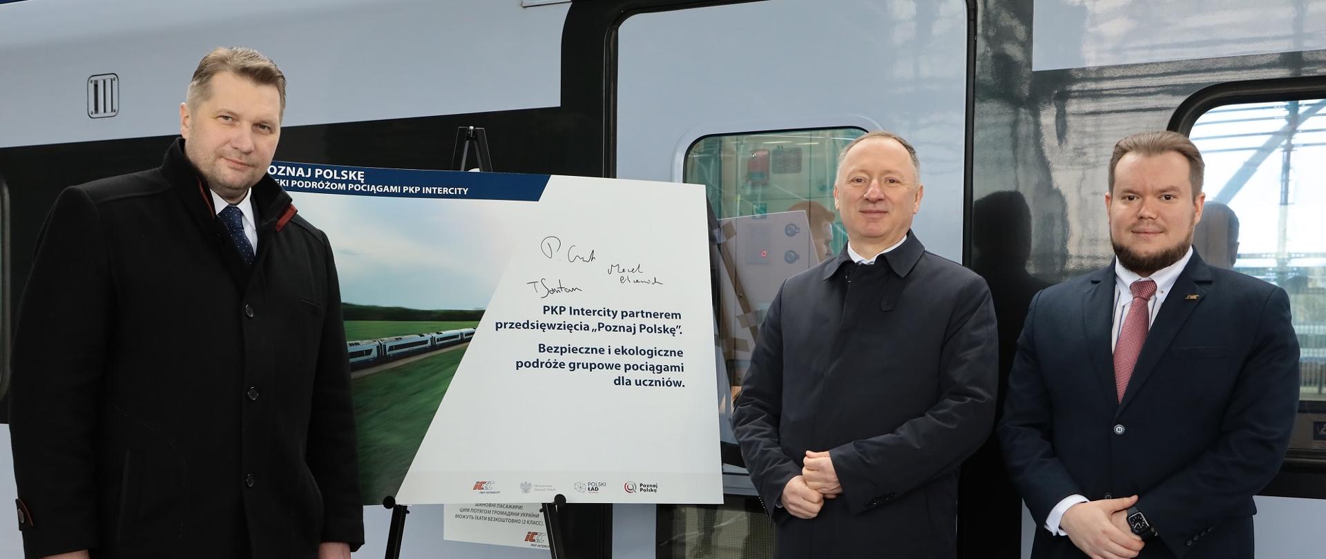 Minister Czarnek stoi przed wagonem kolejowym.