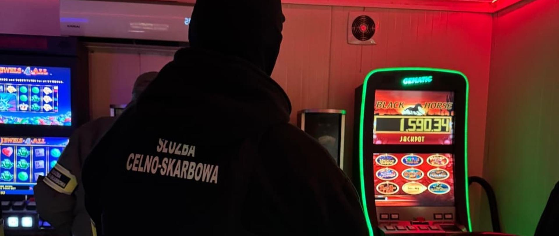 Funkcjonariusz Służby Celno-Skarbowej w nielegalnym salonie gier, przy automatach.