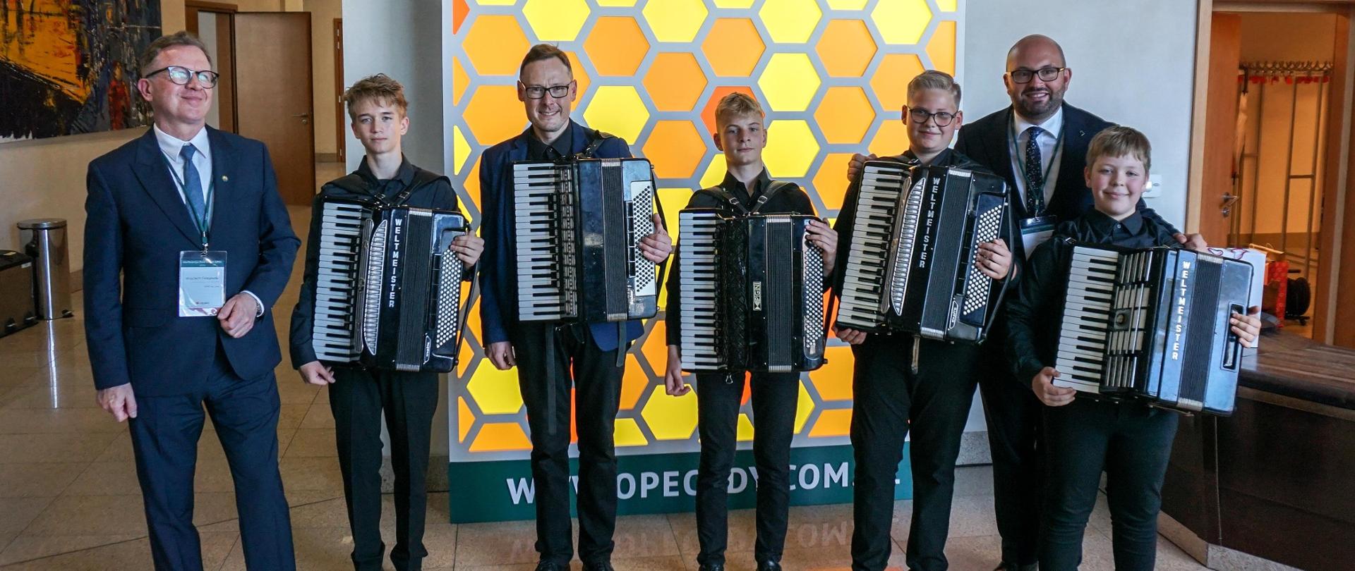 Na tle logo OPEC pozują do zdjęcia akordeoniści oraz prezes OPEC Wojciech Folejewski oraz prezydent Arkadiusz Kraszkiewicz.