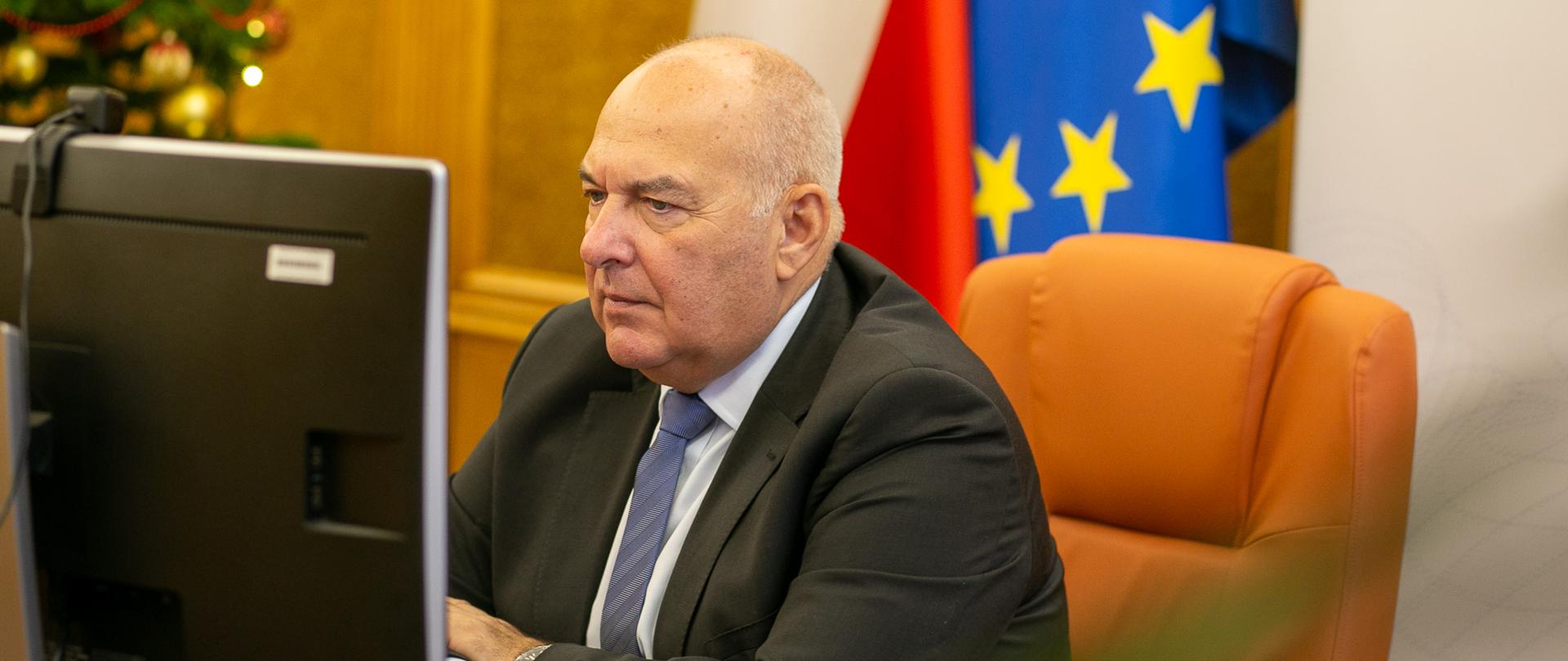 minister Tadeusz Kościński przed monitorem uczestniczy w konferencji online