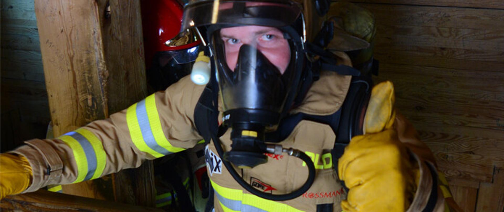 Strażak biegnący po schodach w aparacie ochrony układu oddechowego.