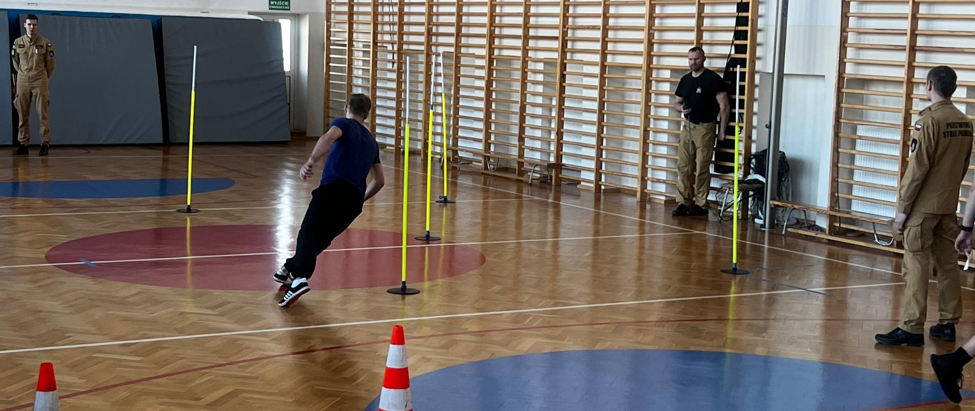 Fotografia przedstawia potencjalnego kandydata do naboru do służby w PSP wykonującego próbny bieg po kopercie - element procesu rekrutacji w PSP