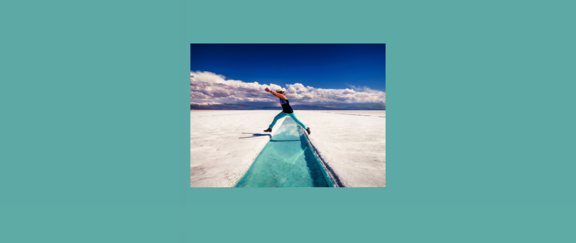 Człowiek przeskakujący przez mały strumyk. Wokół piasek. Z tyłu widać lekko zachmurzone niebo.