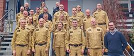 Dwudziestoosobowa grupa funkcjonariuszy i pracowników PSP województwa opolskiego pozuje do zdjęcia grupowego na schodach przed budynkiem w Turawie. Dziewiętnaście osób w mundurach PSP, jedna w stroju cywilnym. Zdjęcie wykonano podczas narady szkoleniowej w dniach 20–21 listopada 2025 roku.
