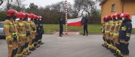 Zdjęcie przedstawia funkcjonariuszy PSP podczas wciągana flagi na maszt. 