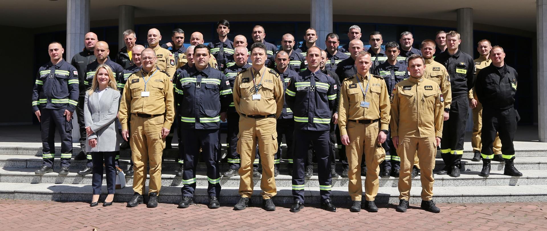 Grupowe zdjęcie gruzińskich strażaków w towarzystwie Komendanta Centralnej Szkoły PSP, dwóch Zastępców Komendanta CS PSP, dwóch oficerów Komendy Głównej PSP, kobiety oraz przedstawicieli PSP i CS PSP
