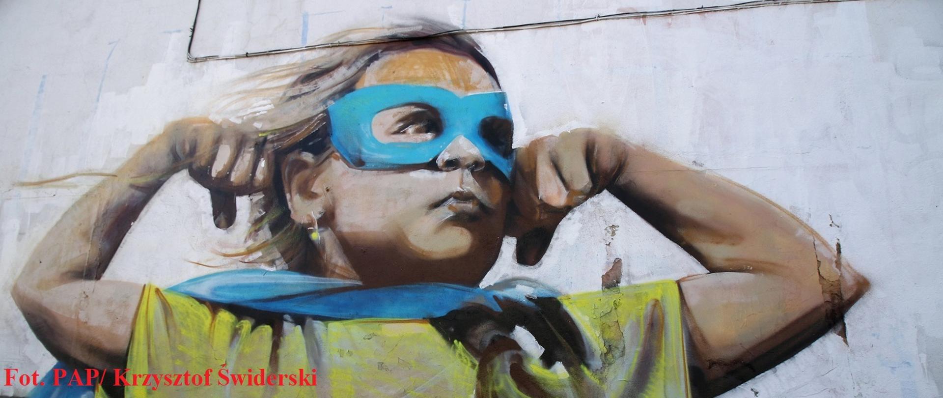 Kędzierzyn-Koźle, 09.03.2022. Mural na starym domu stojącym na skrzyżowaniu ul. Kozielskiej z ul. Przechodni¹ w Kędzierzynie-Koźlu, 9 bm. Dziewczynka w stroju supermana w narodowych barwach Ukrainy pokazuje gest mocy i walki. To dzieło twórcy, który chce pozostaje anonimowy. (aldg) PAP/Krzysztof Świderski