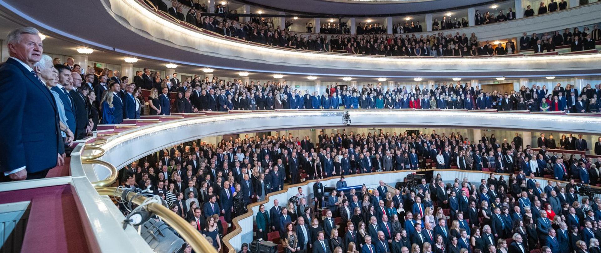Widok sali z lotu ptaka - goście stoją podczas odśpiewania hymnu narodowego