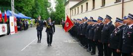 Widok z przodu. Przegląd pododdziałów. Po prawej stronie pododdział OSP. Przeglądu dokonuje Małopolski Komendant Wojewódzki, za nim Dowódca uroczystości. 