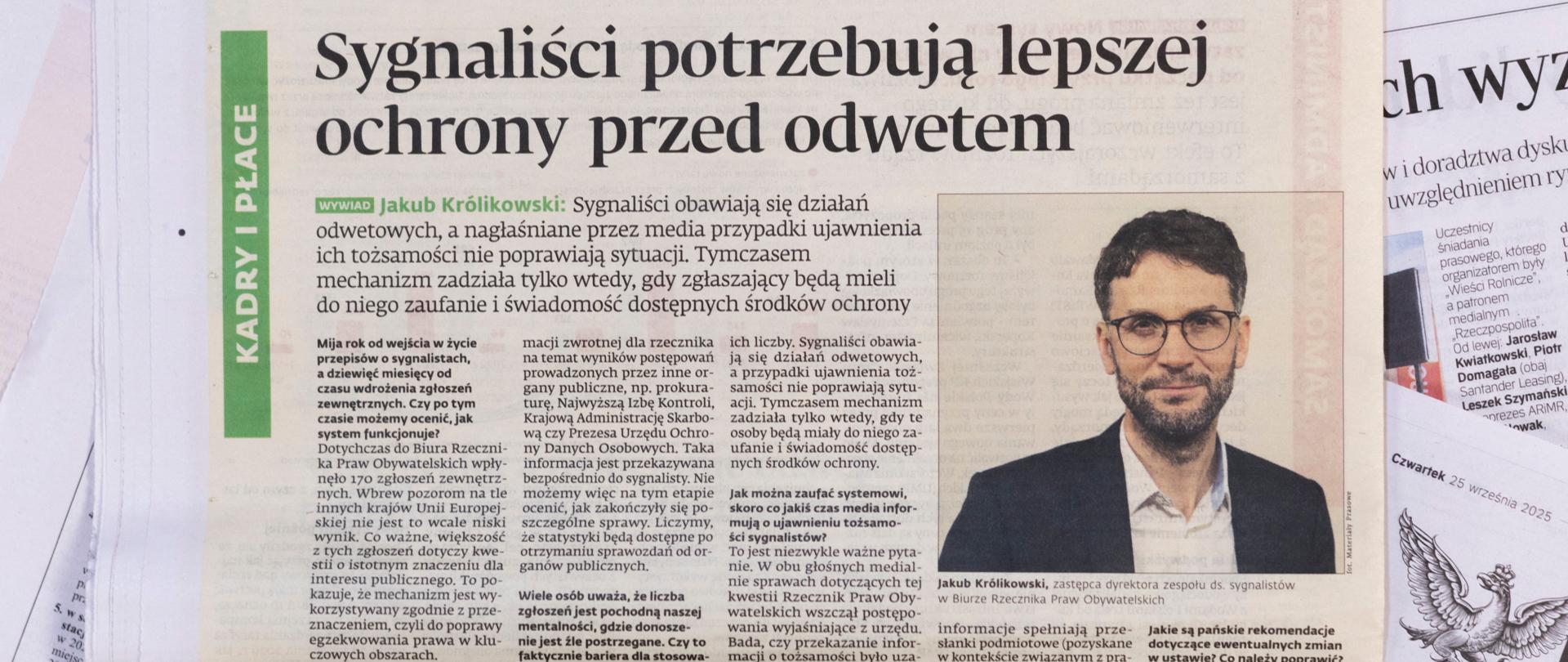 Zdjęcie strony gazety z wywiadem i dużym zdjęciem Jakuba Królikowskiego. Nad wywiadem jest duży tytuł "Sygnaliści potrzebują lepszej ochrony przed odwetem".