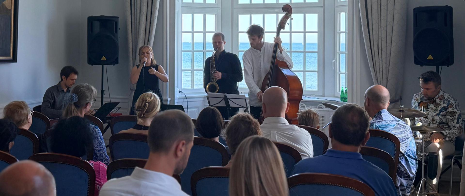 Koncert jazzowy projektu Mellem–Lawiracje–Verdener w Ambasadzie RP w Kopenhadze. Muzycy występują przed licznie zgromadzoną publicznością.