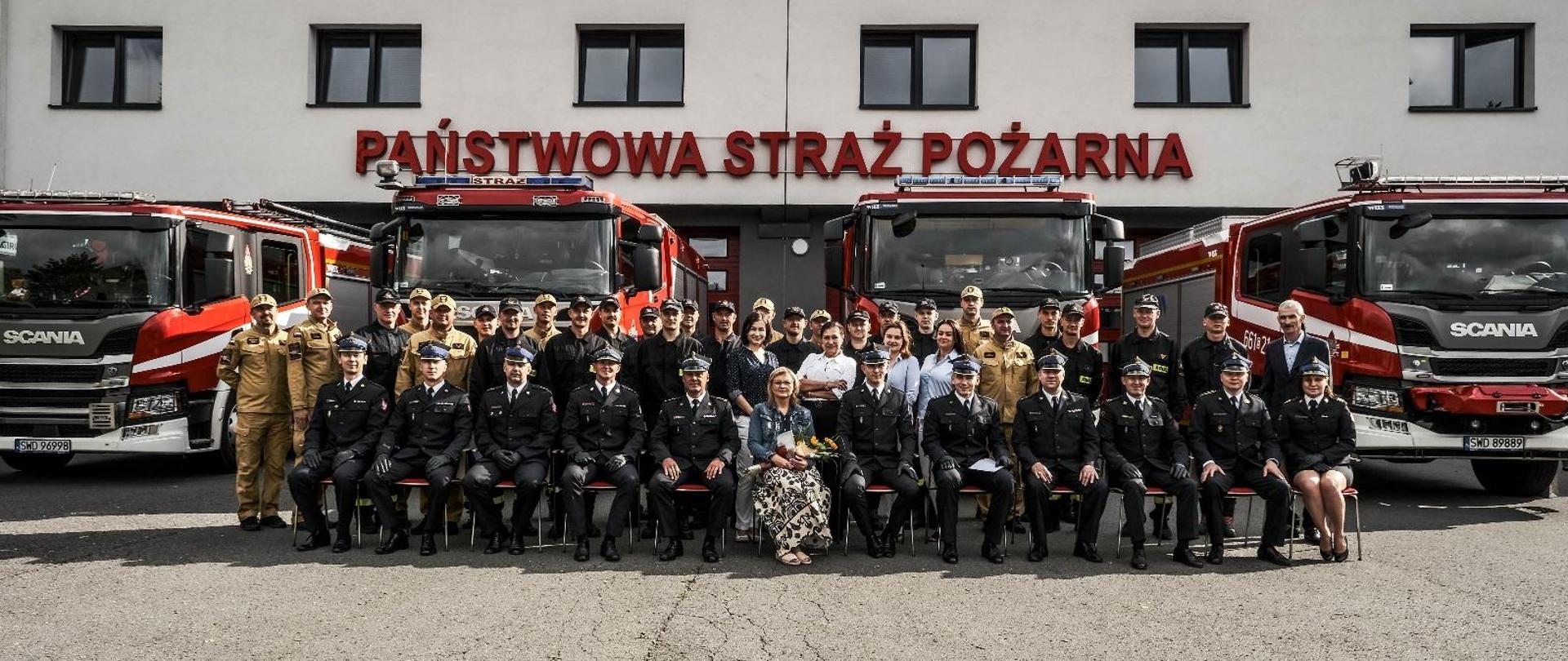 Zdjęcie grupowe pracowników i funkcjonariuszy komendy powiatowej straży pożarnej na tle budynku komendy