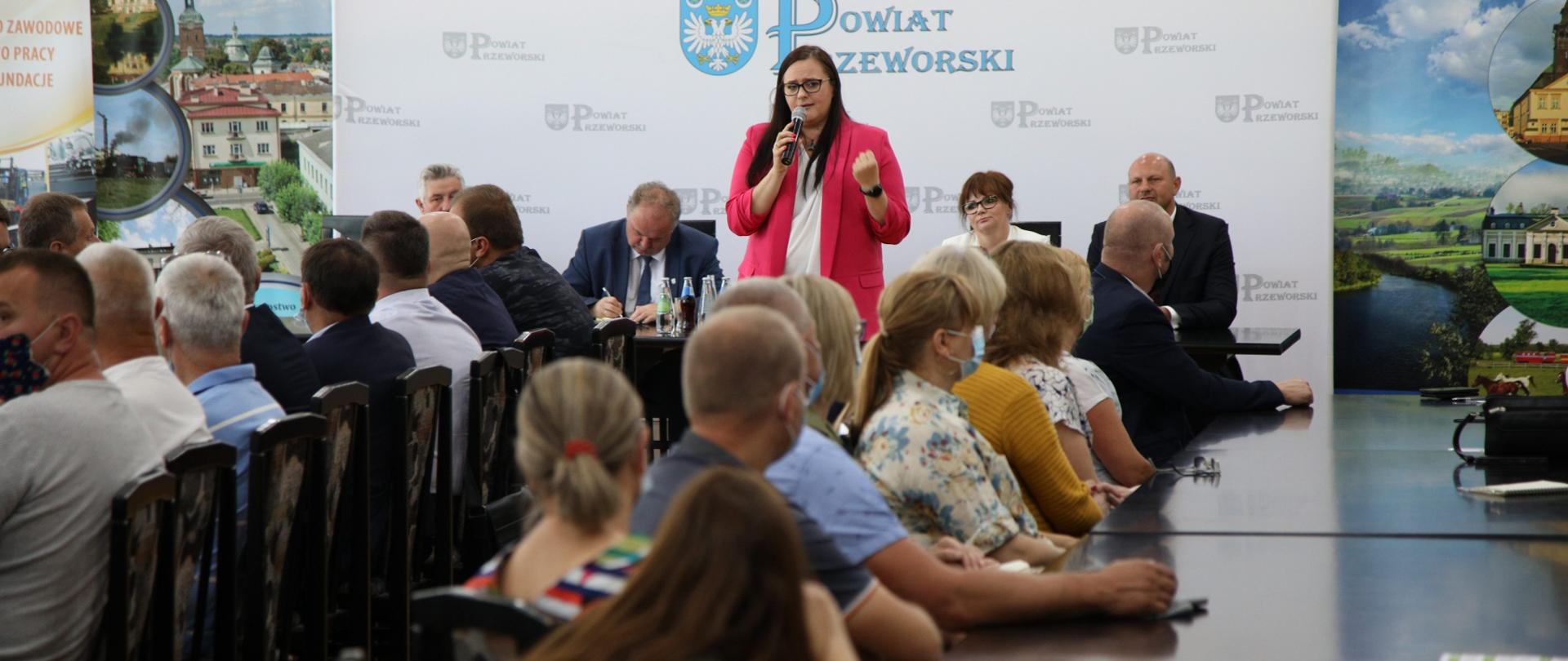 Minister Małgorzata Jarosinska-Jedynak stoi przodem i mówi do osób siedzących przy stołach