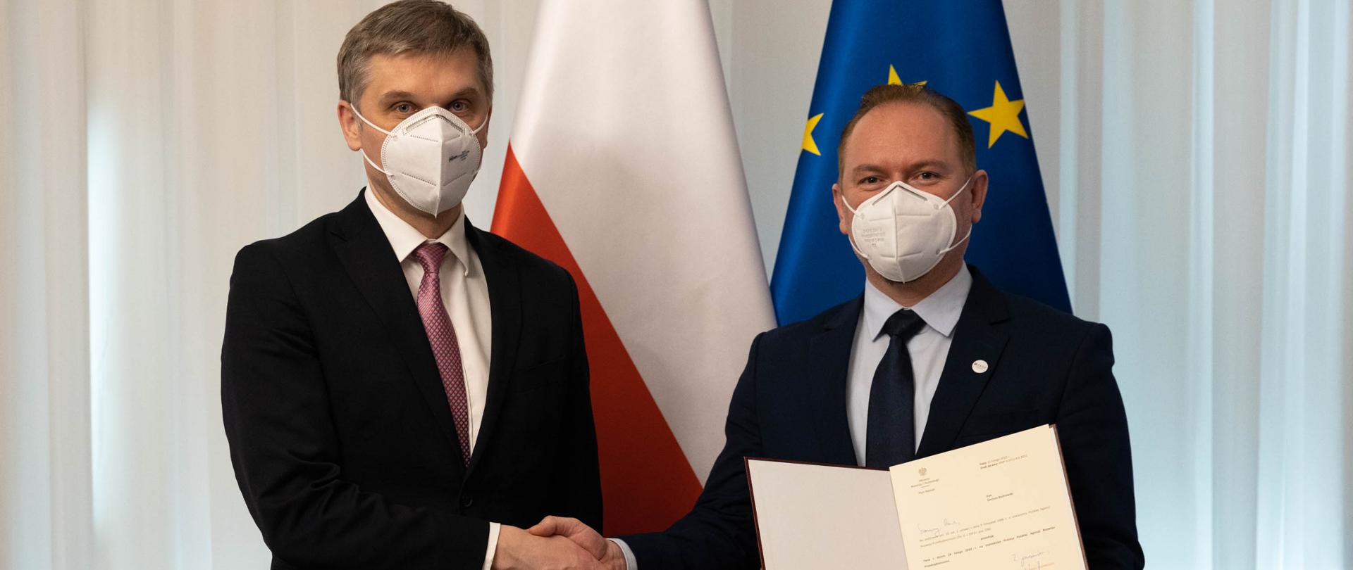 Minister rozwoju i technologii Piotr Nowak ściska dłoń Dariuszowi Budrowskiemu, który w drugiej dłoni trzyma akt powołania na stanowisko Prezesa Polskiej Agencji Rozwoju Przedsiębiorczości 