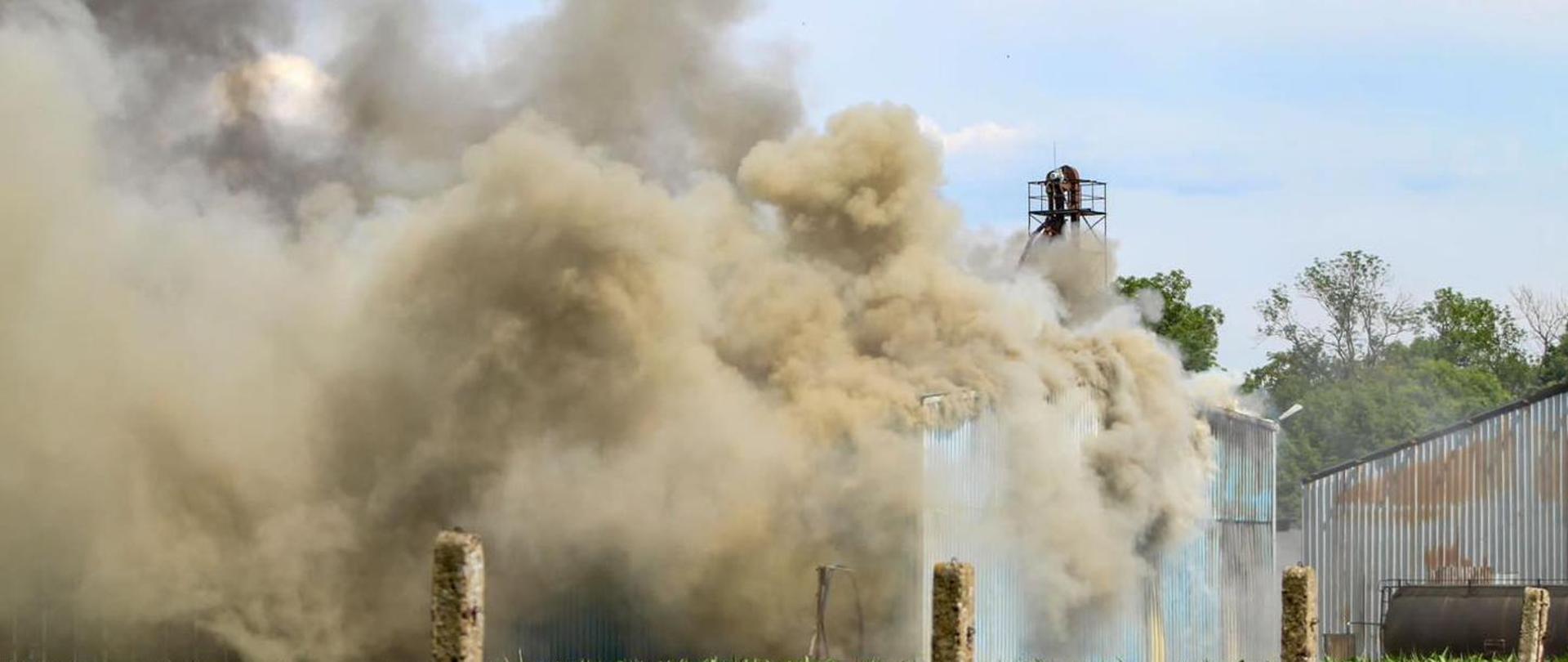 Zdjęcie przedstawia hale magazynową i wydobywający się gęsty dym