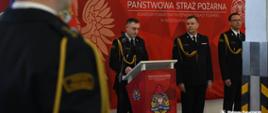 Strażak przemawia przy mównicy, następuje przywitanie gości
