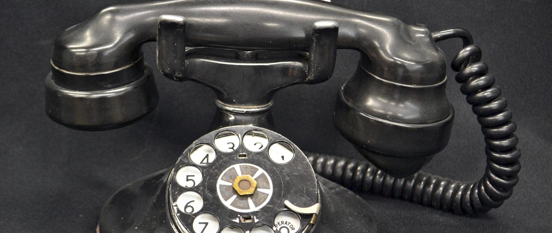 na czarnym tle czarny telefon stacjonarny ze słuchawką na sznurze