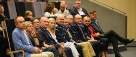 Zaproszeni goiście oraz przedstawiciele służb mundurowych siedzą na fotelach.