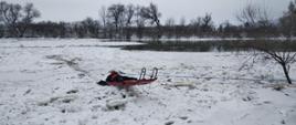Na zdjęciu strażak na saniach lodowych na rzece San częściowo pokrytej lodem ratuje psa