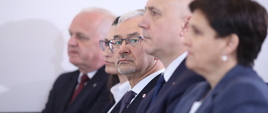 Na zdjęciu 5 osób siedzących w pierwszym rzędzie podczas konferencji. W środku, trzeci od lewej, minister Jerzy Kwieciński.